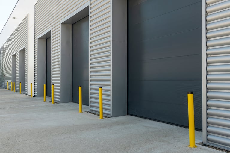 Exterior of an industrial unit with metal roller shutter doors showing commercial garage door installation