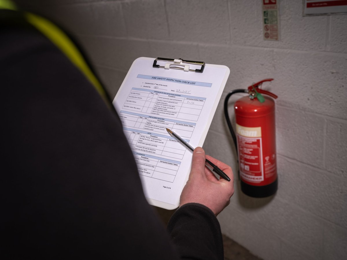 Professional security inspector carrying out fire safety inspection with checklist