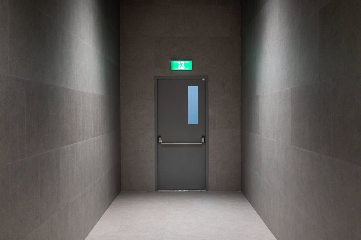 Modern emergency exit door in minimalist dark hallway with safety sign