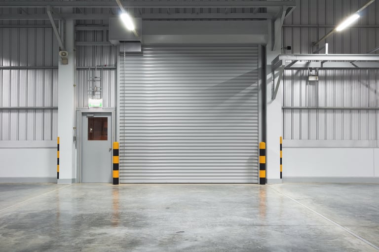 Concrete floor and industrial rolling shutter door inside warehouse building at night in Coquitlam BC