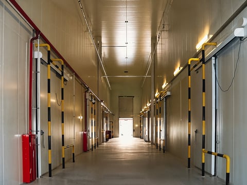 Industrial hallway with series of doors and overhead lighting