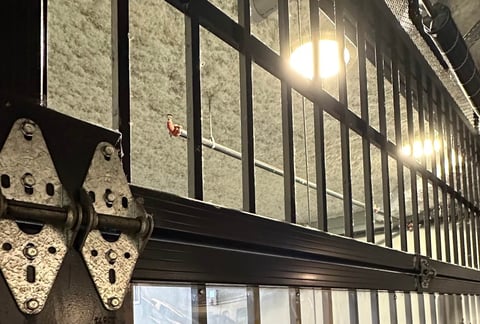 Metal gate with decorative hinges lit by warm night lights on a stone wall