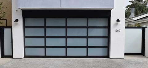 Modern black glass garage door with geometric grid pattern on white house facade