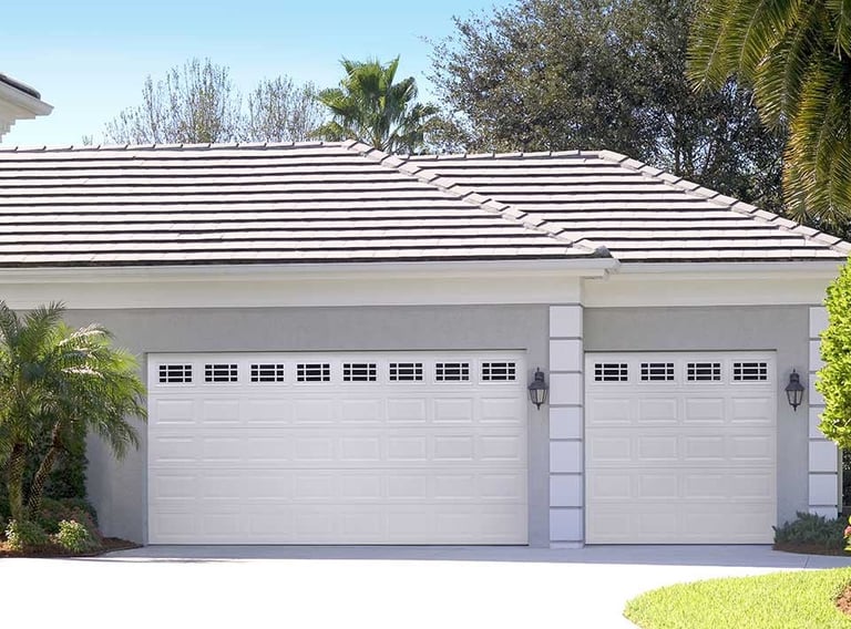 White two-car garage with striped roof and landscaping