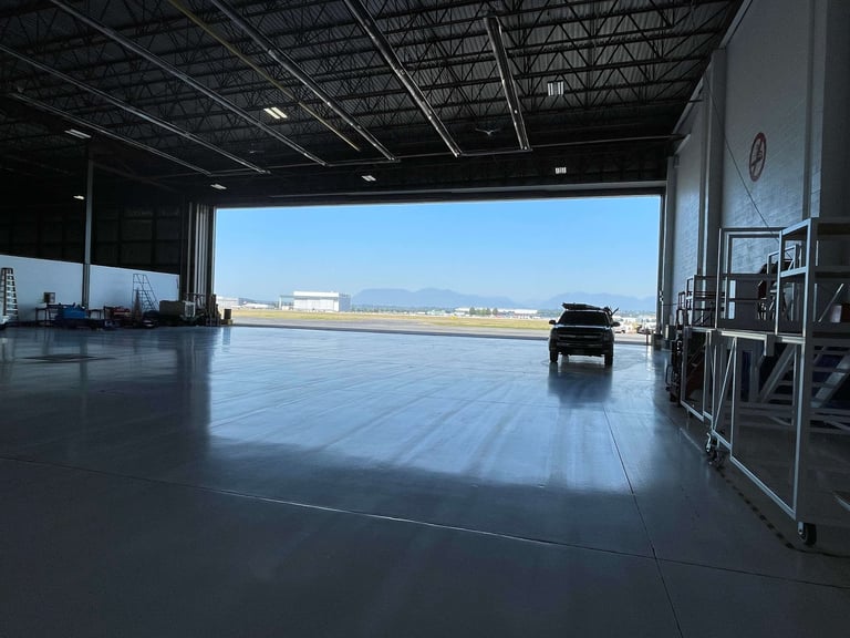 Industrial hangar door installation at private aviation facility with SUV and mountain views in Fraser Valley BC