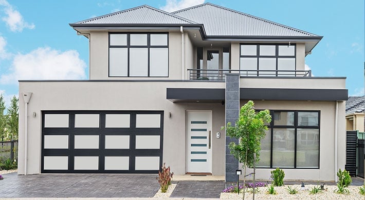 Modern two-story house with white and gray facade, black grid garage door, large windows, and landscaped front yard