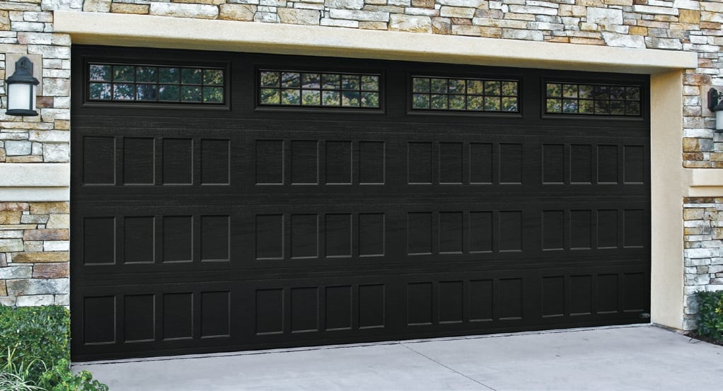 Black modern garage door with horizontal panel design and glass windows on a stone and stucco house facade