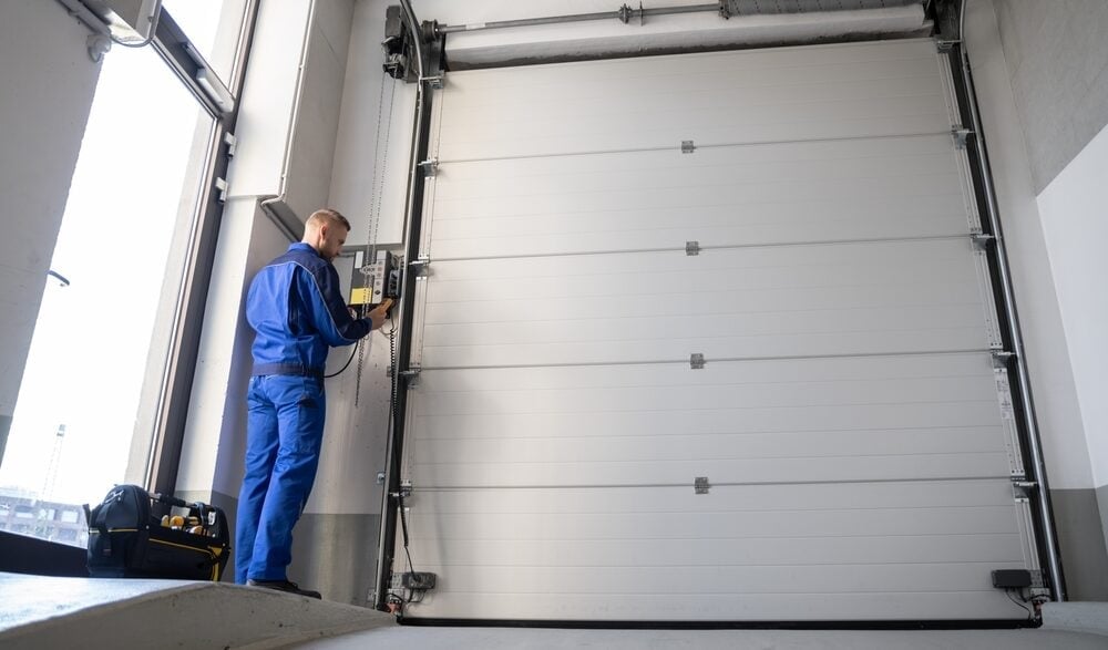 Professional technician in blue uniform working on garage door installation or maintenance in Coquitlam BC for Lower Mainland homes