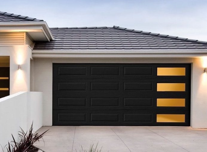 Modern black garage door with gold accent panels on contemporary house with white walls and tile roof