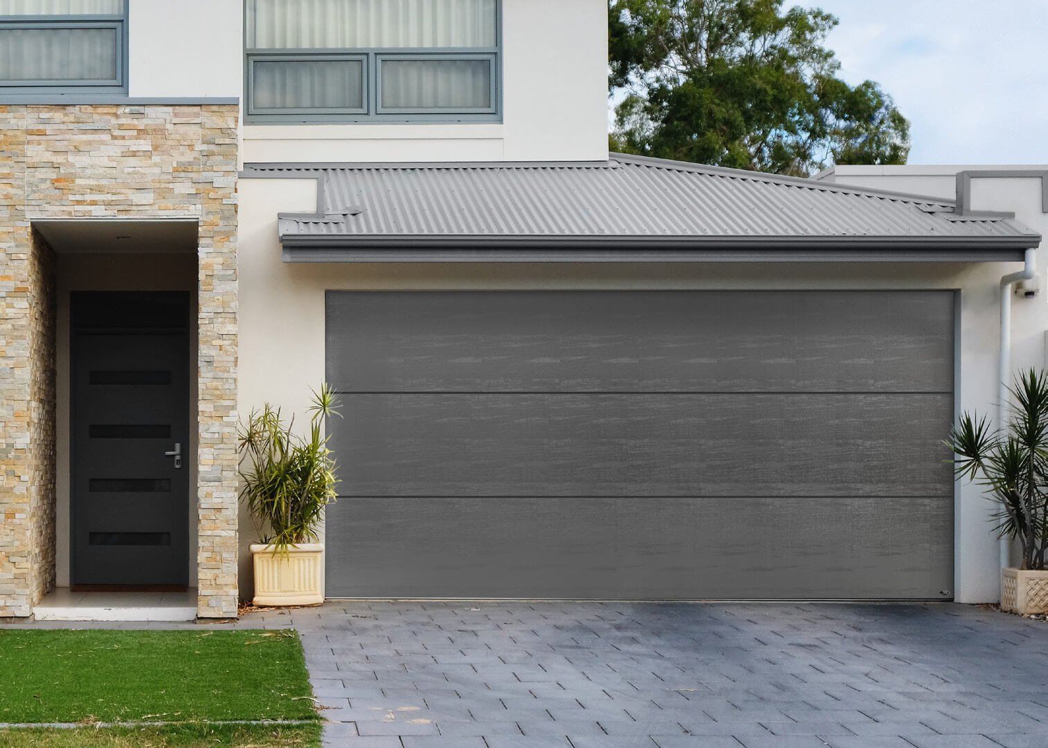 Modern two-story home with dark gray garage door, black entry door, brick and white exterior, and paved driveway