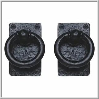 Pair of antique black iron ring handles mounted on weathered metal plates with decorative details