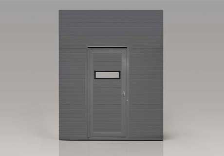 Gray corrugated metal structure with a single horizontal ribbed door featuring a small rectangular window and handle