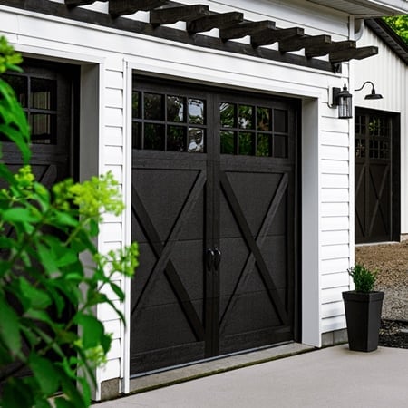 Modern garage with black X-pattern doors, white siding, and lattice pergola above entry
