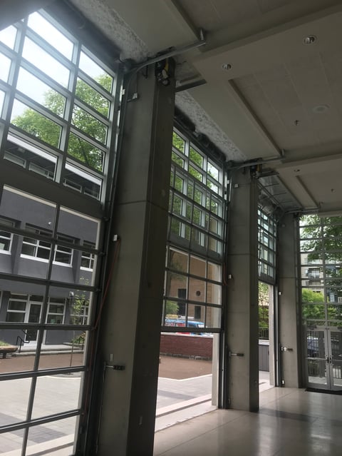 Interior view of industrial garage with multiple black frame glass doors opening to a brick courtyard