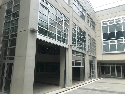 Modern concrete building courtyard with large gridded windows and open entrance, minimalist architectural design