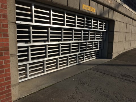 White and black horizontal slatted garage door on brick building wall