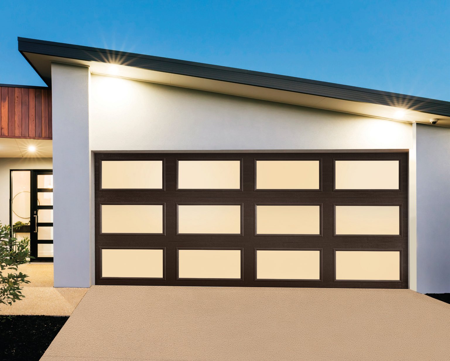 Modern white garage with black framed glass panel doors on a contemporary house exterior