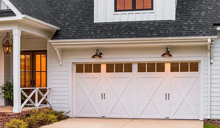 Modern white farmhouse exterior with double garage doors, charcoal roof, and landscaping