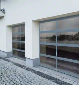 Modern garage with two glass doors on a white-walled building with cobblestone driveway