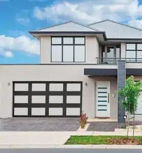 Modern two-story white house with black garage door, white entry door, and large front windows against blue sky